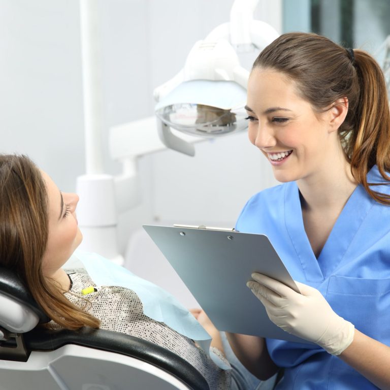 Dentist holding a medical history asking information to a patient before treatment sitting on a chair in a clinic box